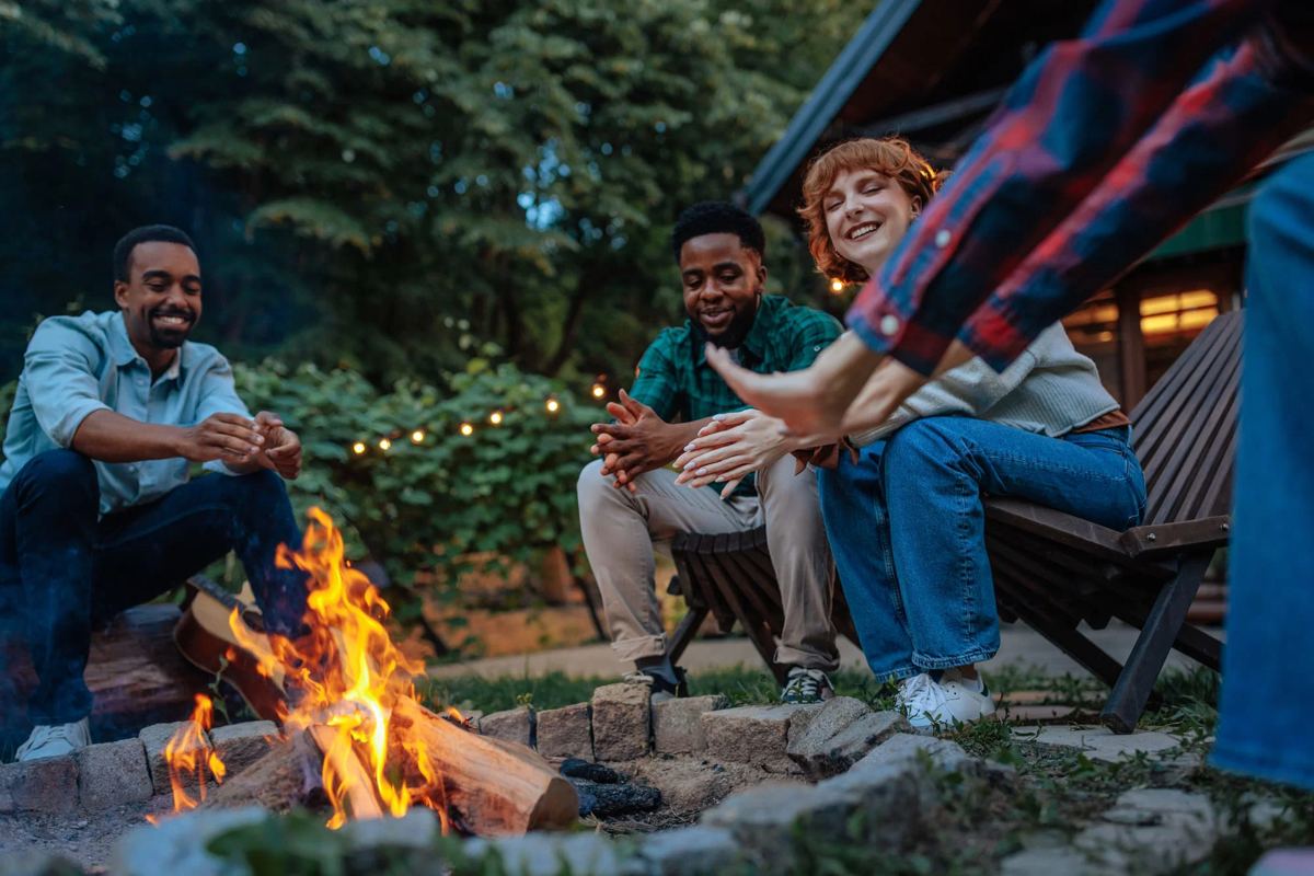A group of friends in recovery laughing around a firepit